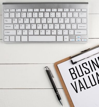 Professional desk with keyboard, clipboard displaying "Business Valuation" text, and pen – symbolizing business exit planning and valuation services.