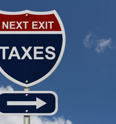 Humorous highway road sign reading "Next Exit: Taxes" against blue sky, illustrating tax planning opportunities under the 2025 OBBBA reforms
