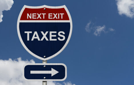 Humorous highway road sign reading "Next Exit: Taxes" against blue sky, illustrating tax planning opportunities under the 2025 OBBBA reforms