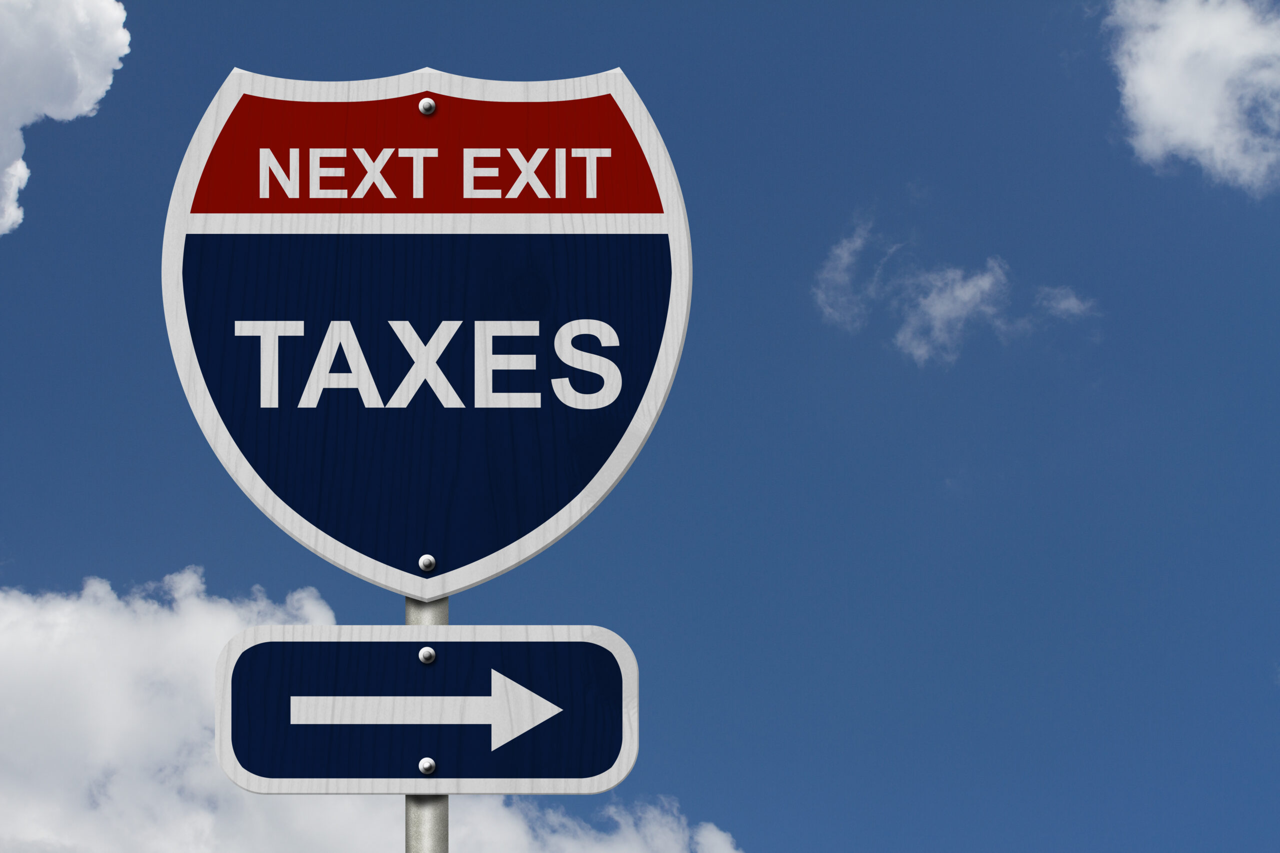 Humorous highway road sign reading "Next Exit: Taxes" against blue sky, illustrating tax planning opportunities under the 2025 OBBBA reforms